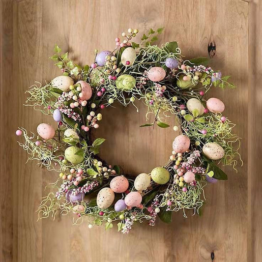 Decorative wreath with Easter eggs and flowers on a wooden door