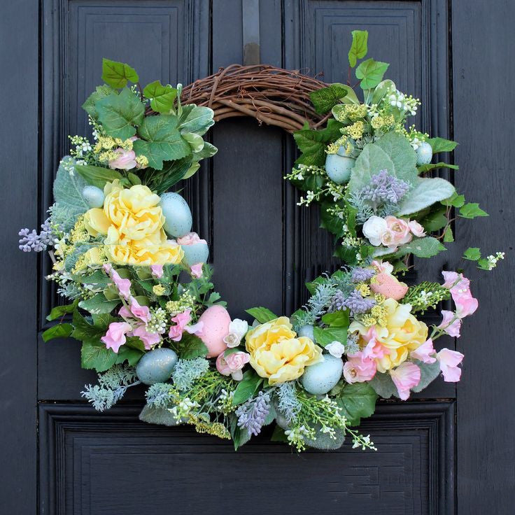 Decorative wreath with flowers and eggs on a dark door