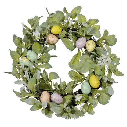 Decorative wreath with green leaves and colorful eggs on a white background