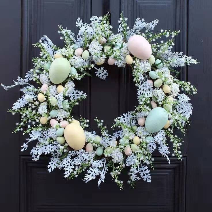 Easter wreath with pastel eggs and greenery on a dark door