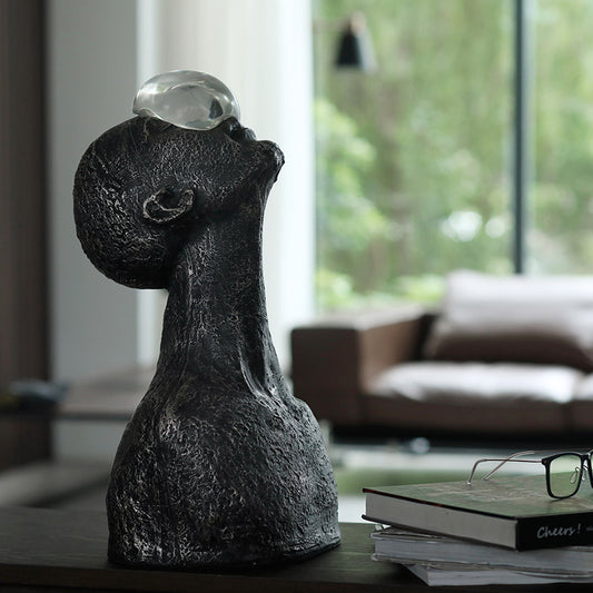 Decorative sculpture of a faceless figure with a crystal ball on a table in a living room.